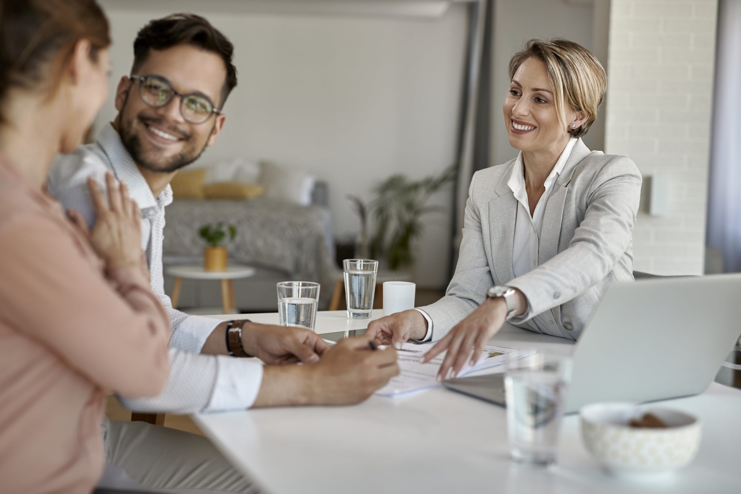 Real estate agent goes over paperwork for a Premium Home Warranty with a happy couple of homeowners.